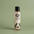 A 100 ml bottle of Velafora Coconut Oil with a black cap and a cream-colored label decorated with botanical illustrations, set against a solid sage green background.

