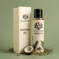 A bottle of Velafora Coconut Oil next to its cream-colored cardboard box, styled with a halved coconut, rosemary sprigs, and a gold spoon on a sage green background.